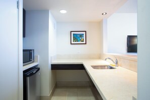 A compact kitchen with a microwave, dishwasher, sink, and a framed picture on the wall.