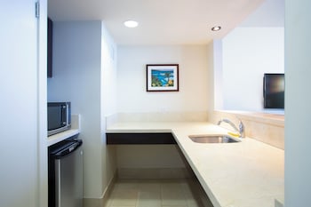 A modern bathroom with a large mirror, two sinks, and a towel rack. at Park Shore Waikiki