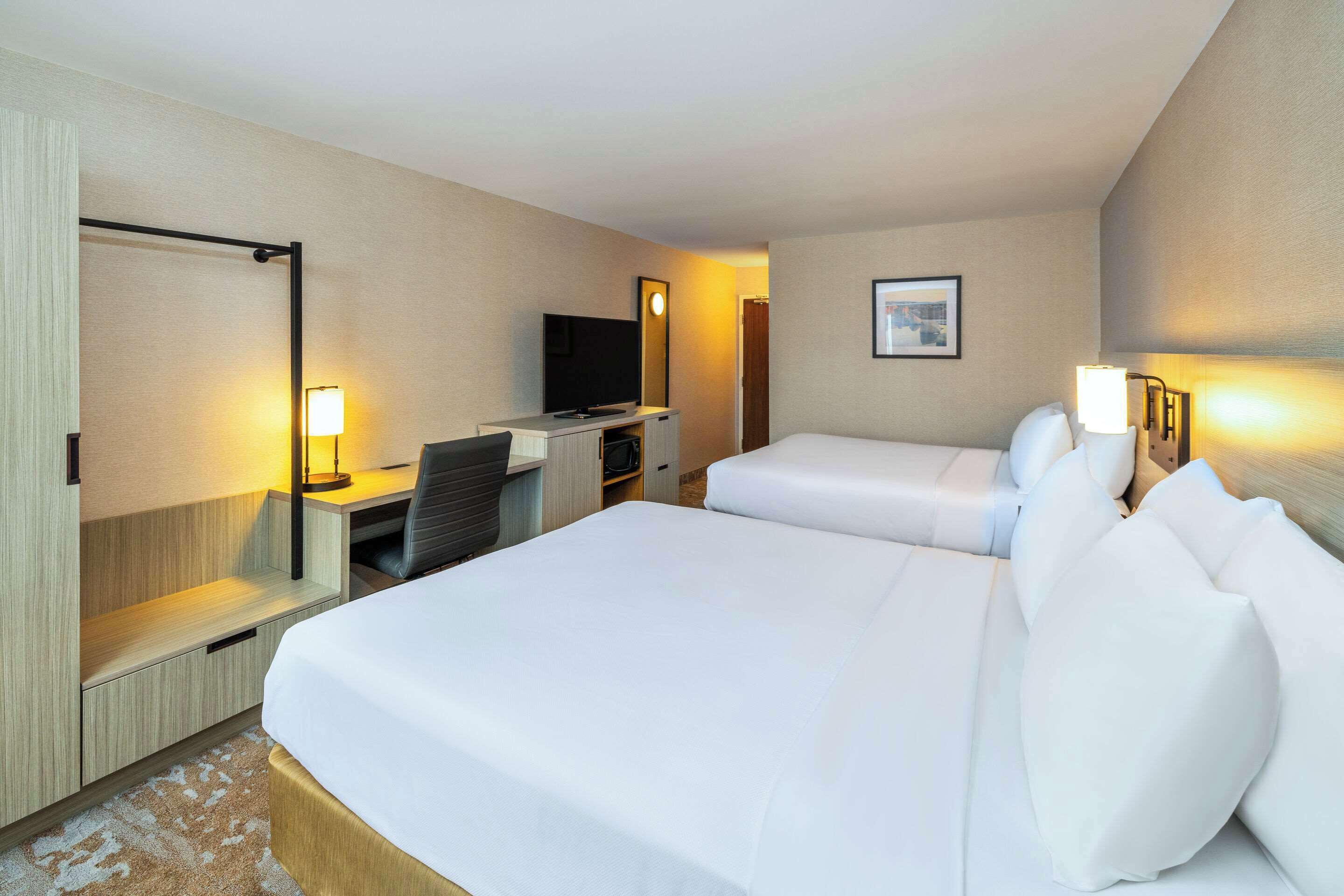 Une chambre d’hôtel avec deux lits, un bureau avec une télévision et un petit coin salon.