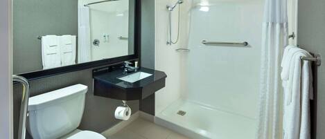 Une salle de bain moderne équipée de toilettes, d’un lavabo et d’une douche à parois de verre.