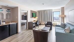 Una habitación de hotel moderna con kitchenette, comedor, sofá y televisión.