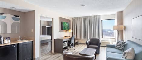 Una habitación de hotel moderna con kitchenette, comedor, sofá y televisión.