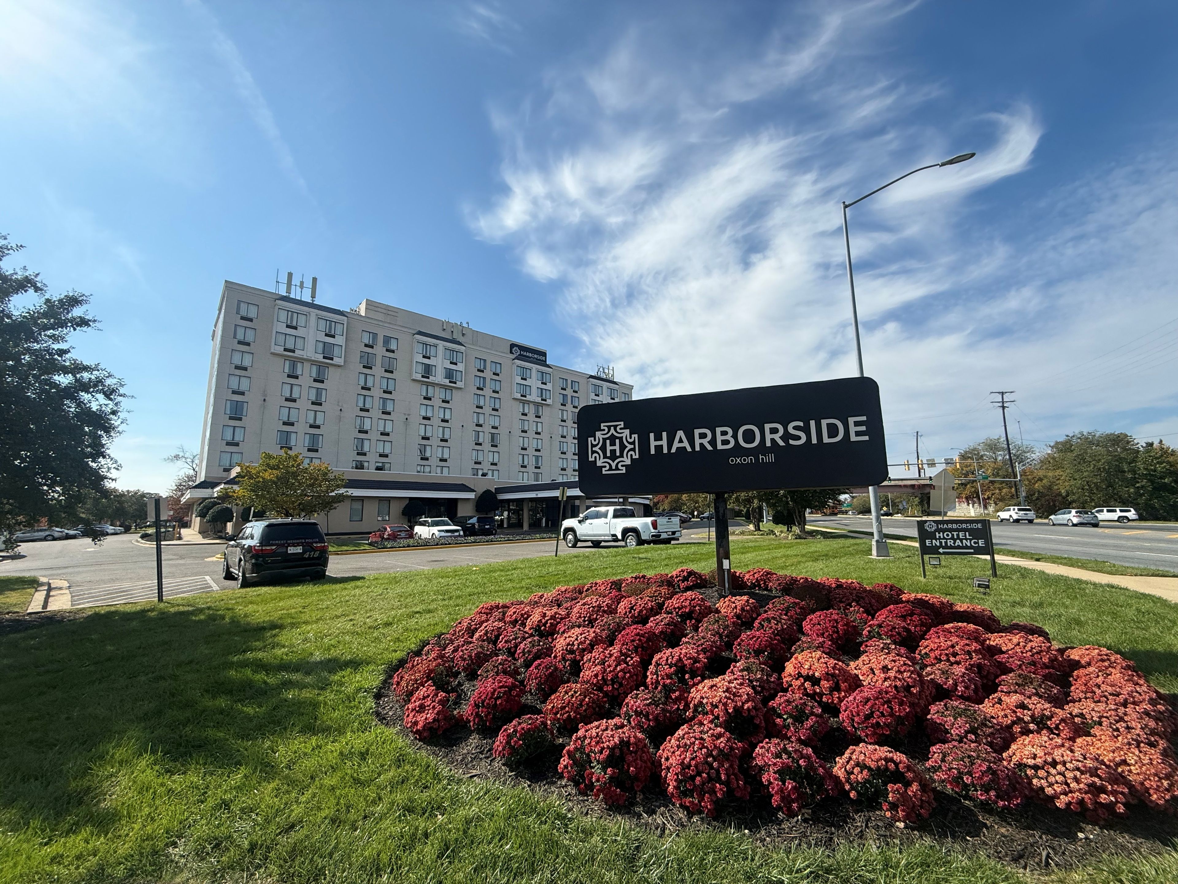 A sign for Harborside Hotel with a view of the building and parked cars.