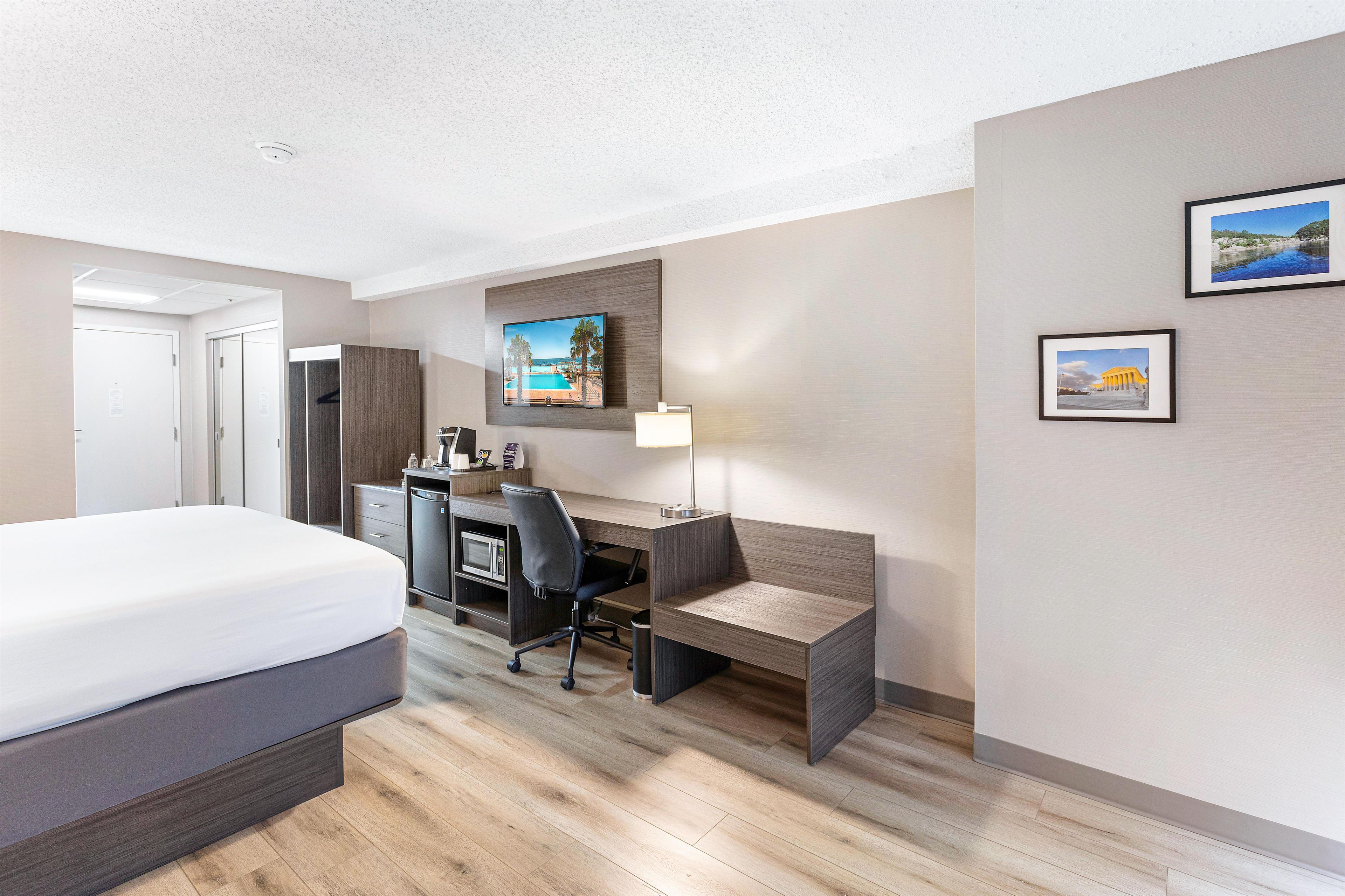 Una habitación de hotel con cama, escritorio, silla y televisor.