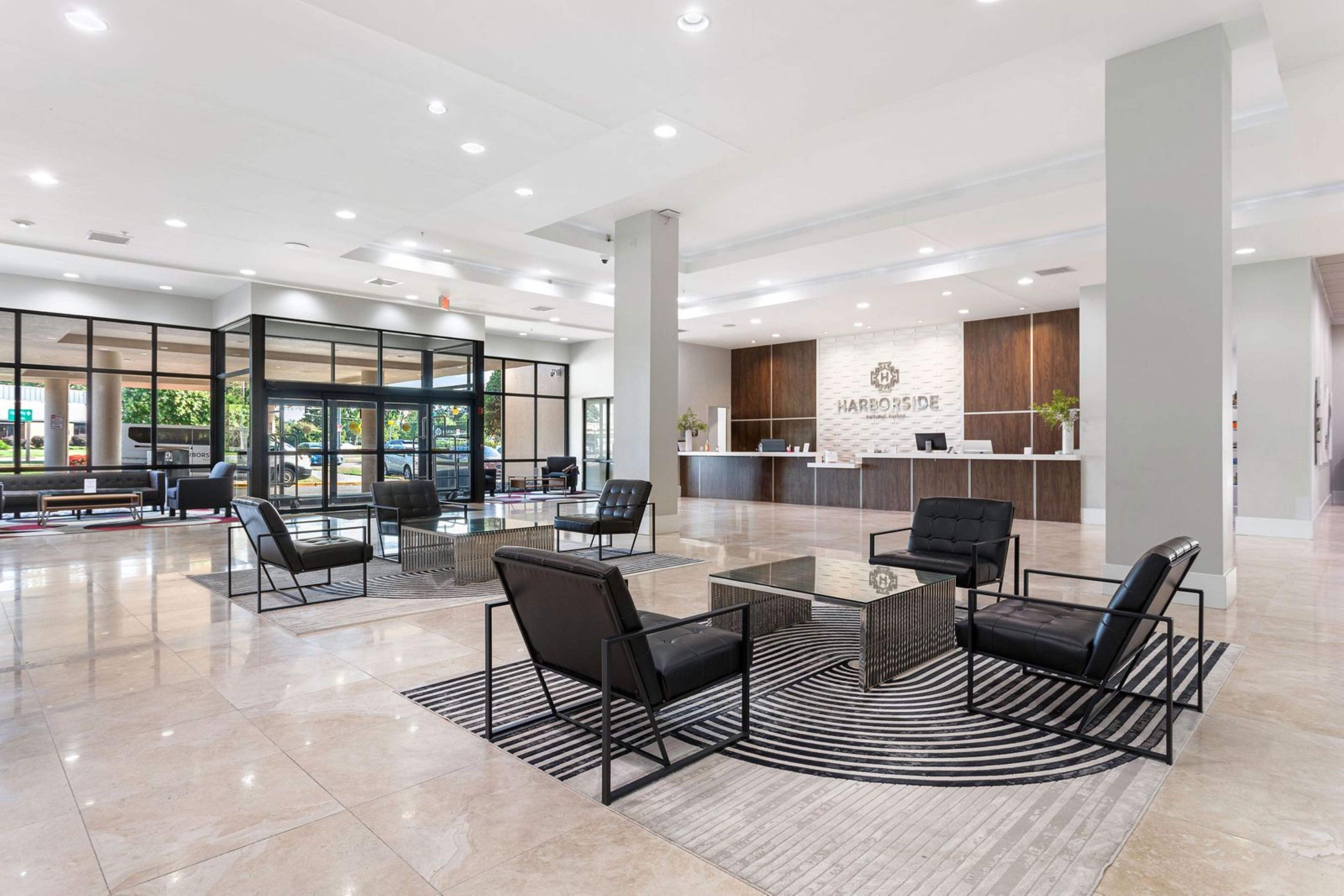 A spacious lobby with a reception desk, seating area, and a view of the parking area.