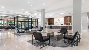 A spacious lobby with a reception desk, seating area, and a view of the parking area.