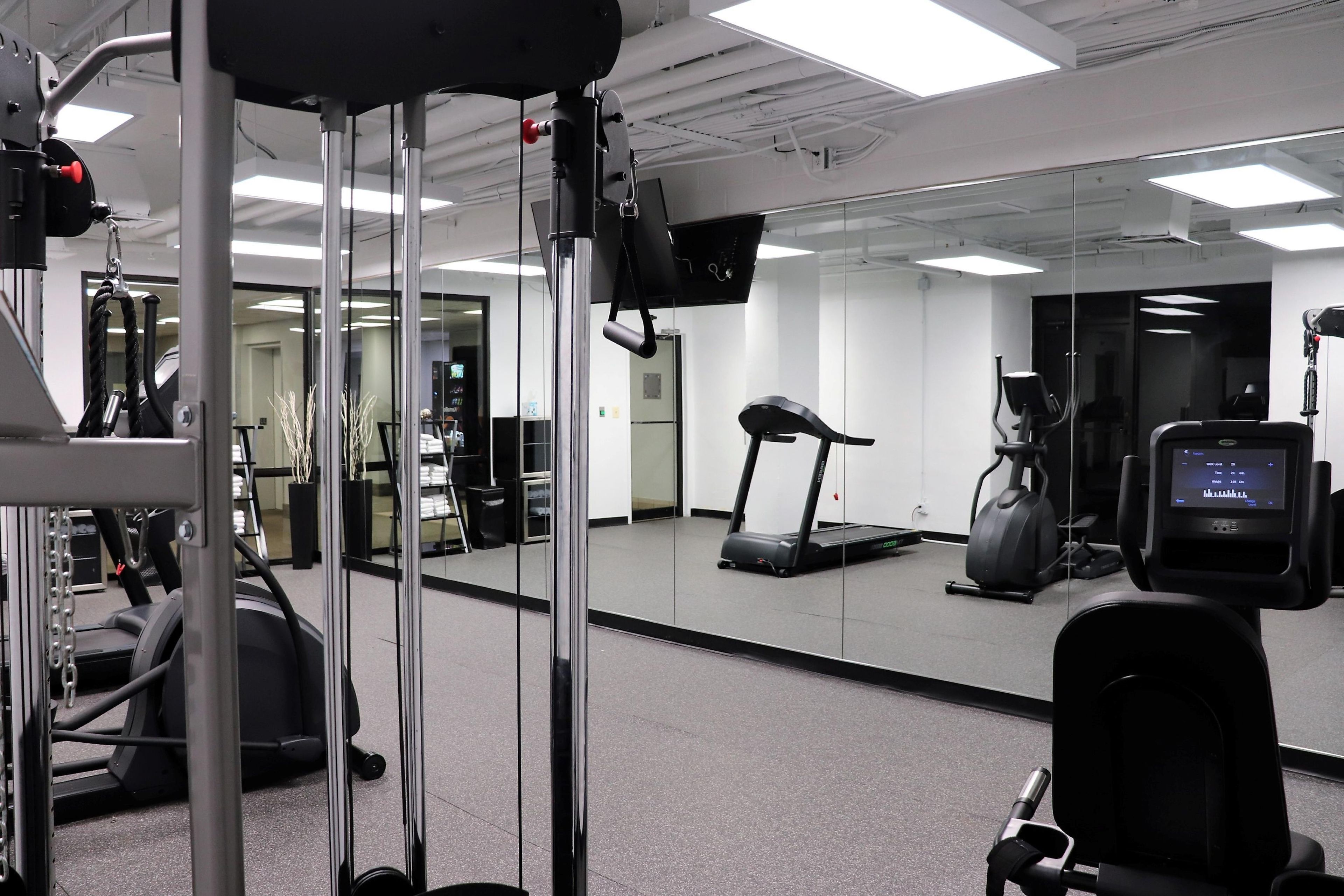 A gym with exercise equipment, a treadmill, and a mirrored wall.