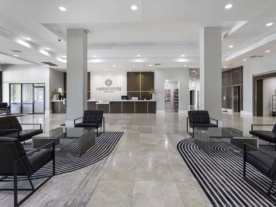 Un moderno vestíbulo de hotel con mostrador de recepción, asientos de cuero negro y un espejo grande.