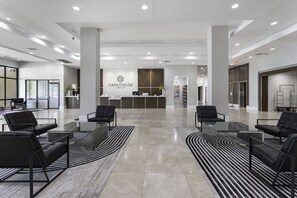 A modern hotel lobby with a reception desk, black leather seating, and a large mirror. - Harborside Hotel (Oxon Hill)