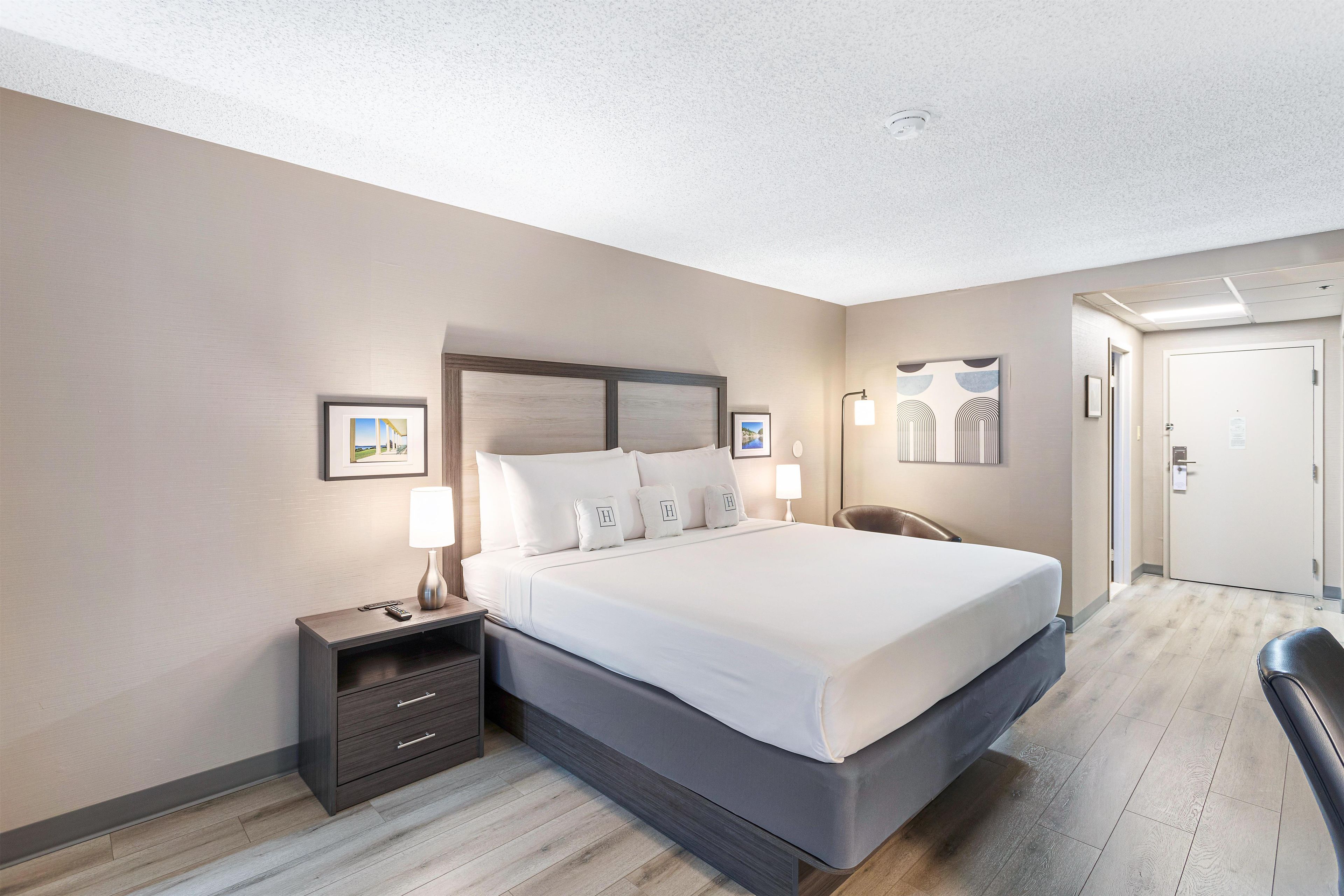 A hotel room with a large bed, bedside tables, a desk, and a chair.