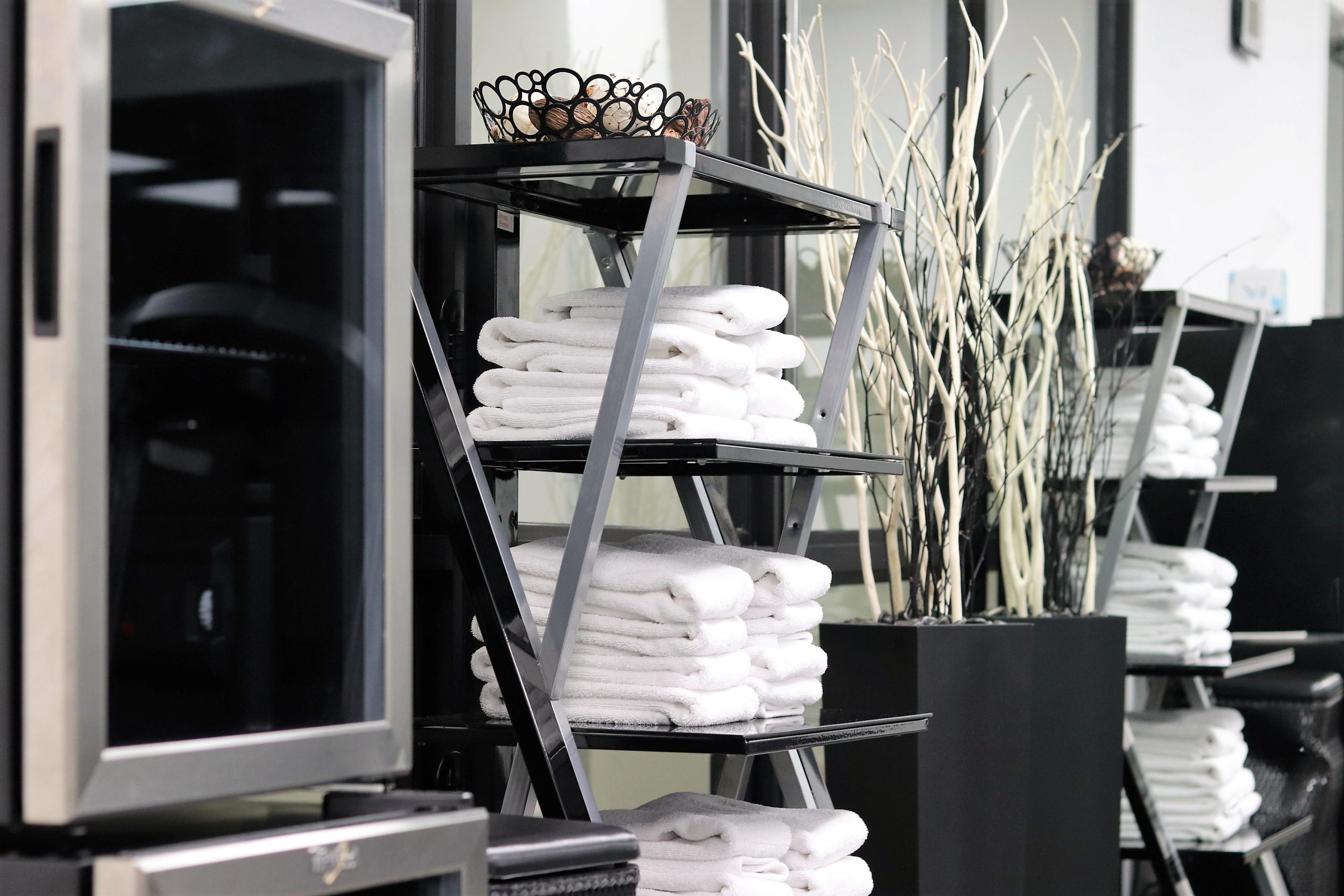 A hotel room with a black metal shelf holding white towels and a decorative bowl.