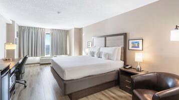 Une chambre d’hôtel avec un grand lit, un bureau, une chaise et une table de chevet avec une lampe.