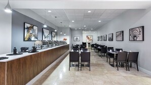 Un comedor moderno con una barra larga, varias mesas y sillas.