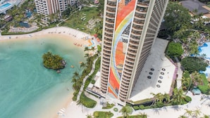 Un hotel de gran altura con vista a la playa, múltiples balcones y una zona de piscina.