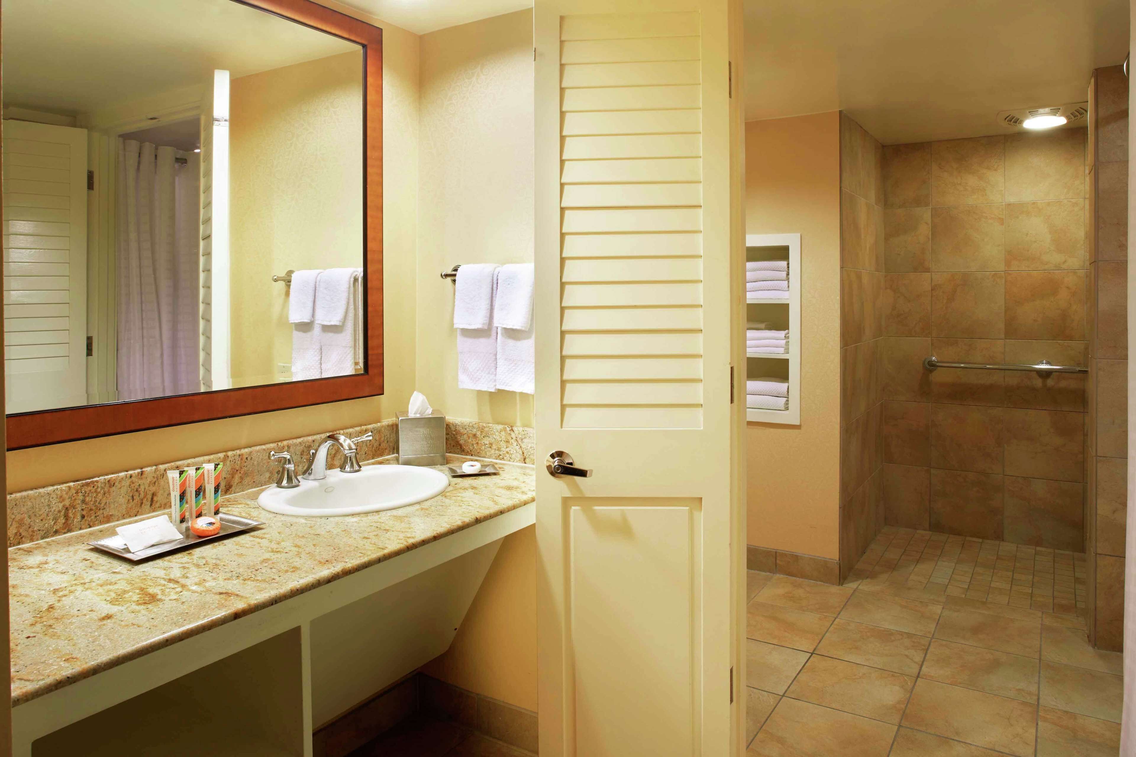A bathroom with a sink, mirror, and shower area.