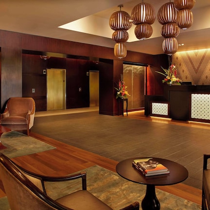 A lobby with wooden flooring, a reception desk, and a seating area with chairs and a table.