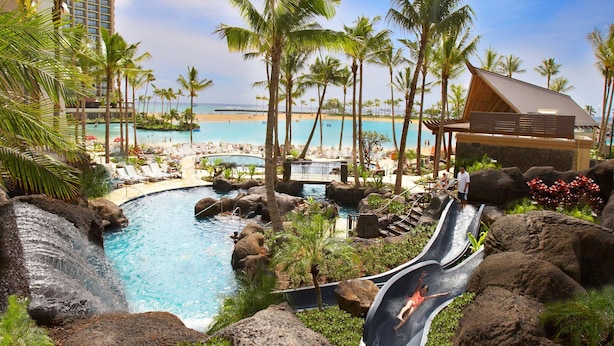 Un resort con piscina, palmeras y vistas a la playa.
