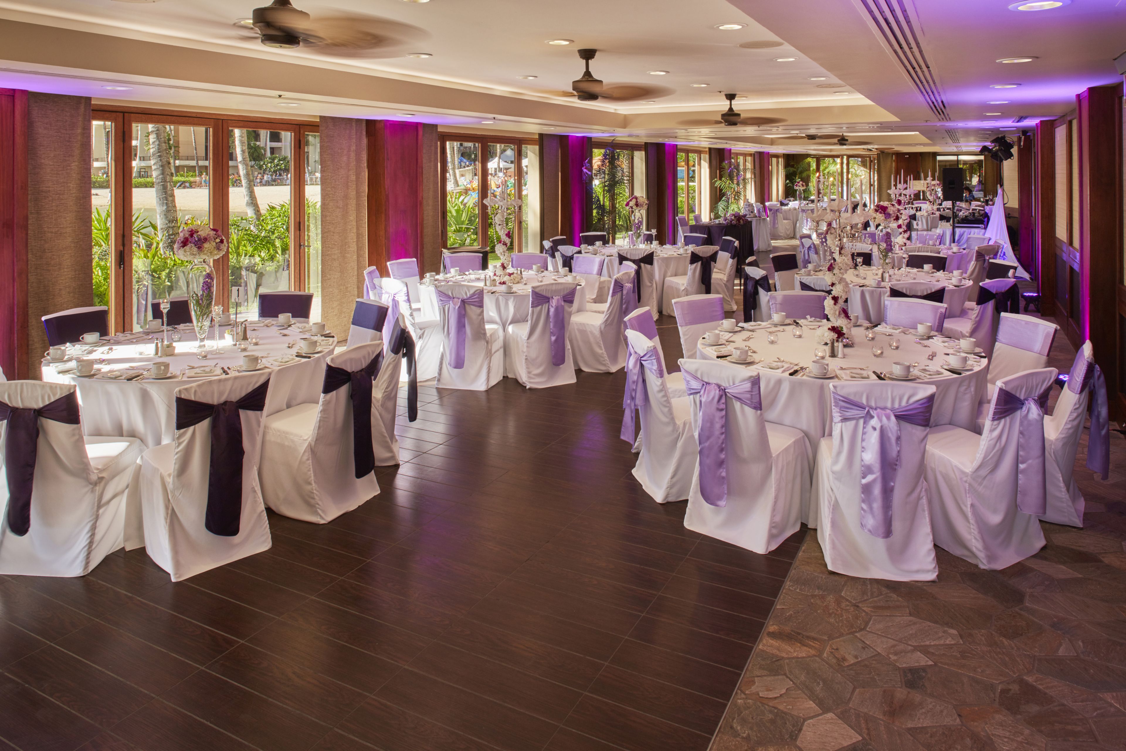 A banquet hall with round tables, white tablecloths, and purple sashes.