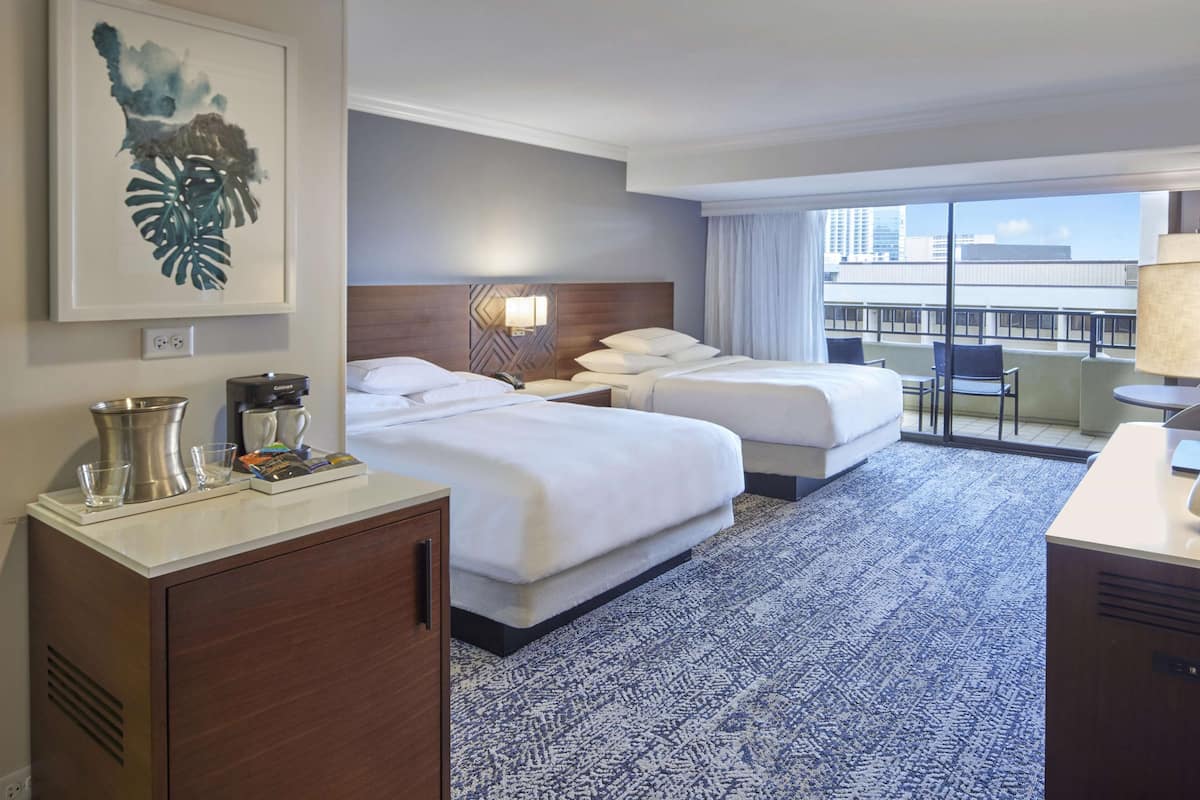 Habitación de hotel con dos camas, un escritorio, un minibar y vistas a la ciudad.