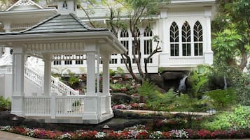 A gazebo with a staircase, surrounded by a garden with various plants and flowers.