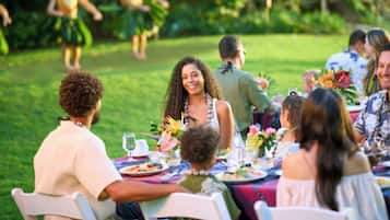 Un grupo de personas sentadas en una mesa de comedor al aire libre, con vista a un jardín.