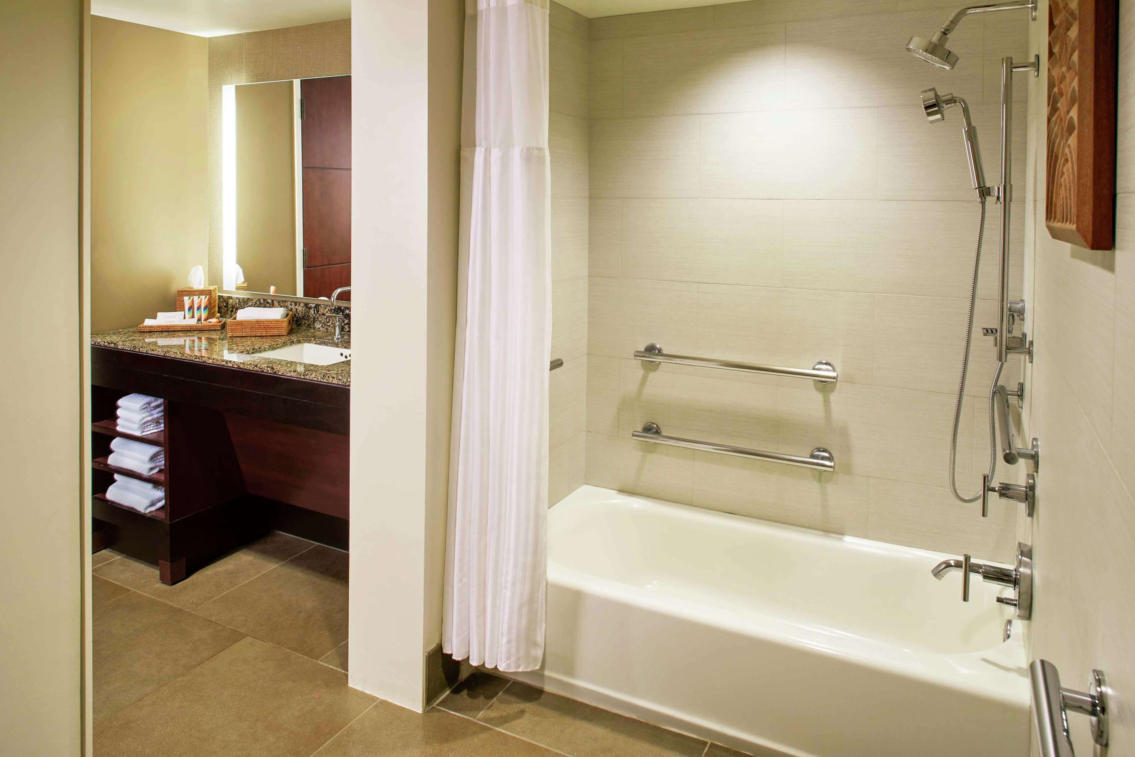 Un baño con bañera, ducha y tocador con espejo.