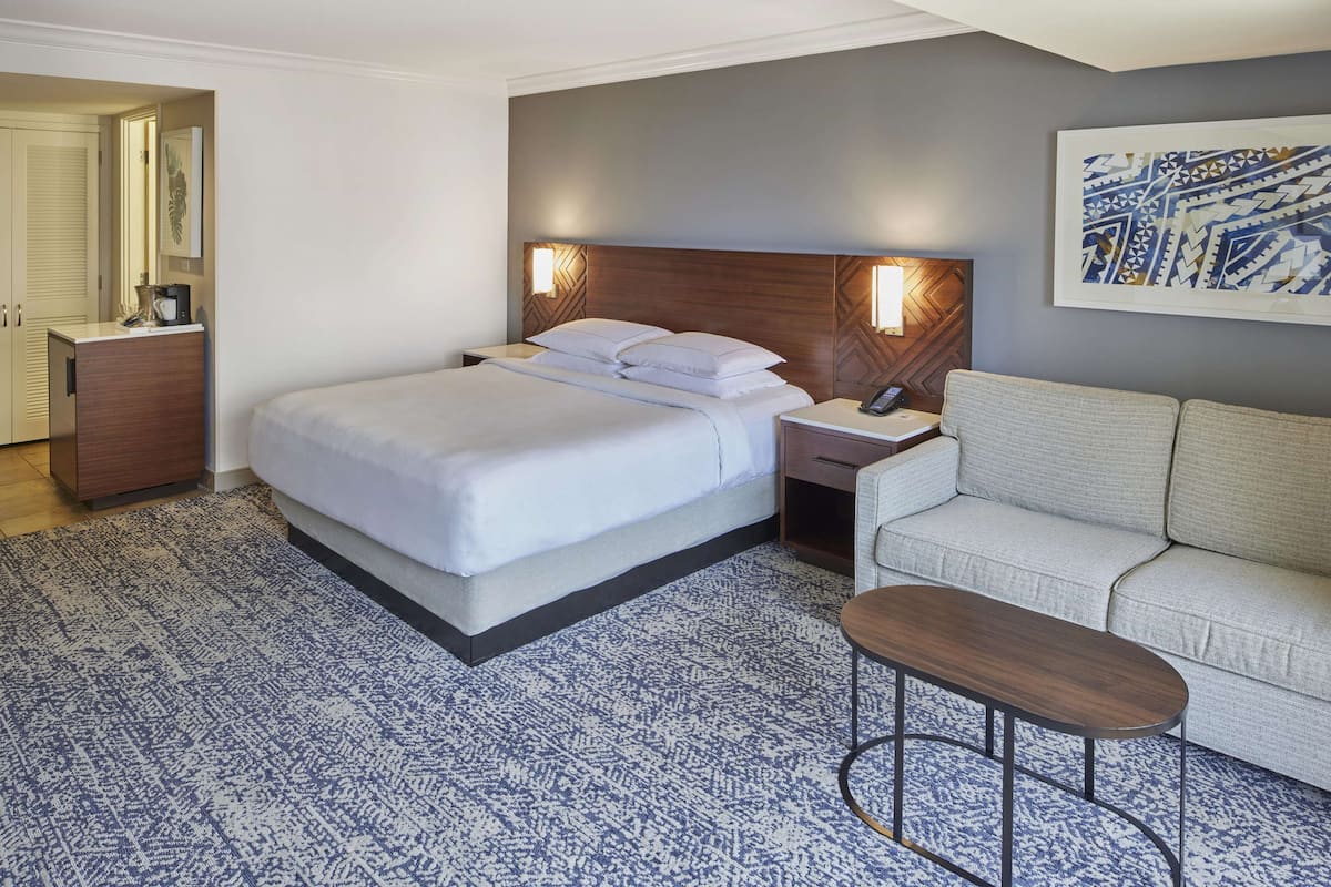 Una habitación de hotel con cama, mesita de noche y sofá.