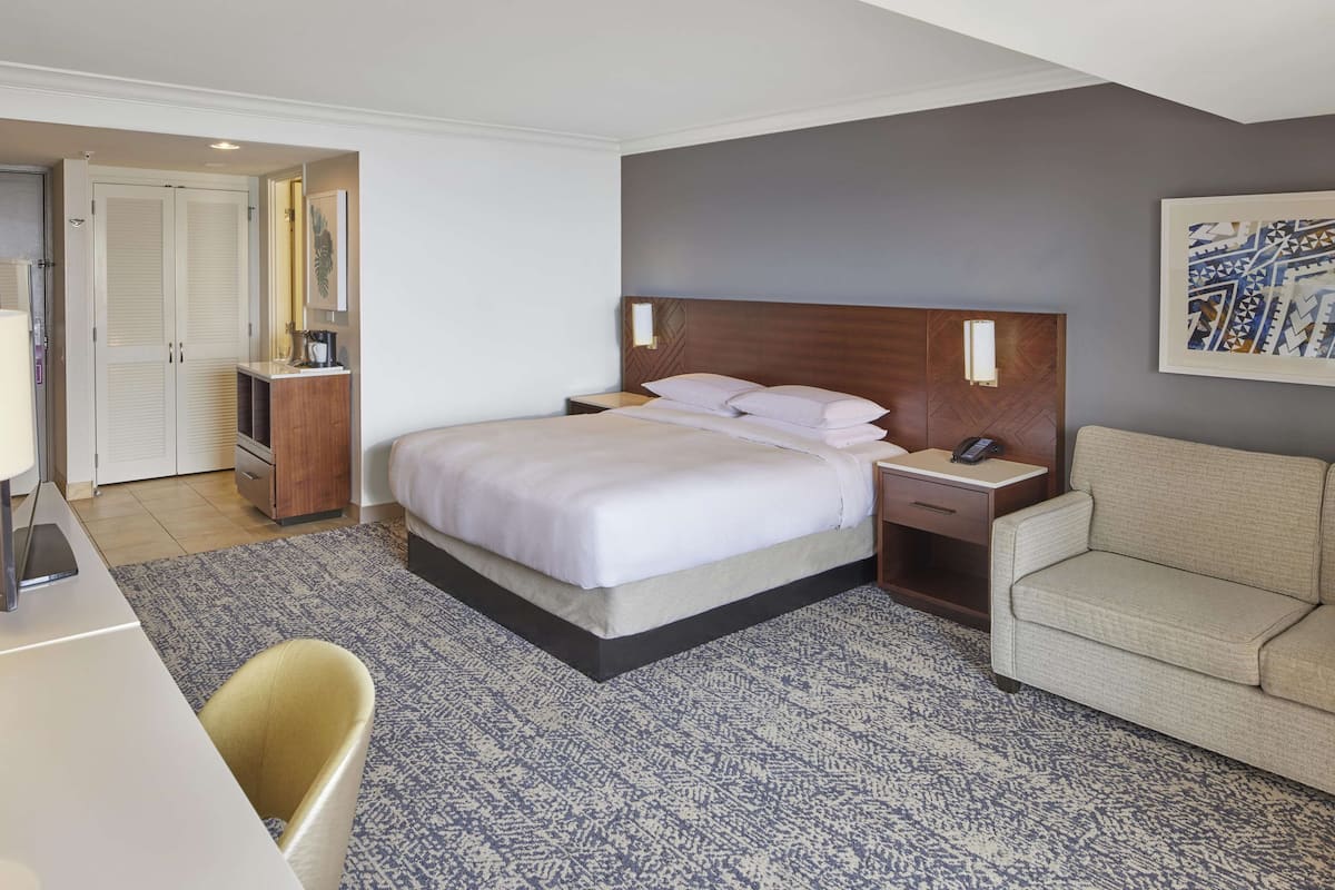 Una habitación de hotel con cama, mesita de noche, silla y escritorio con lámpara.