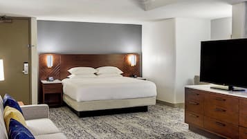 A hotel room with a bed, bedside tables, a television, and a dresser.