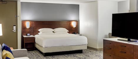 Ein Hotelzimmer mit Bett, Nachttischen, einem Fernseher und einem Schminktisch.