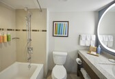 A bathroom with a bathtub, toilet, shower, and a vanity with a mirror.