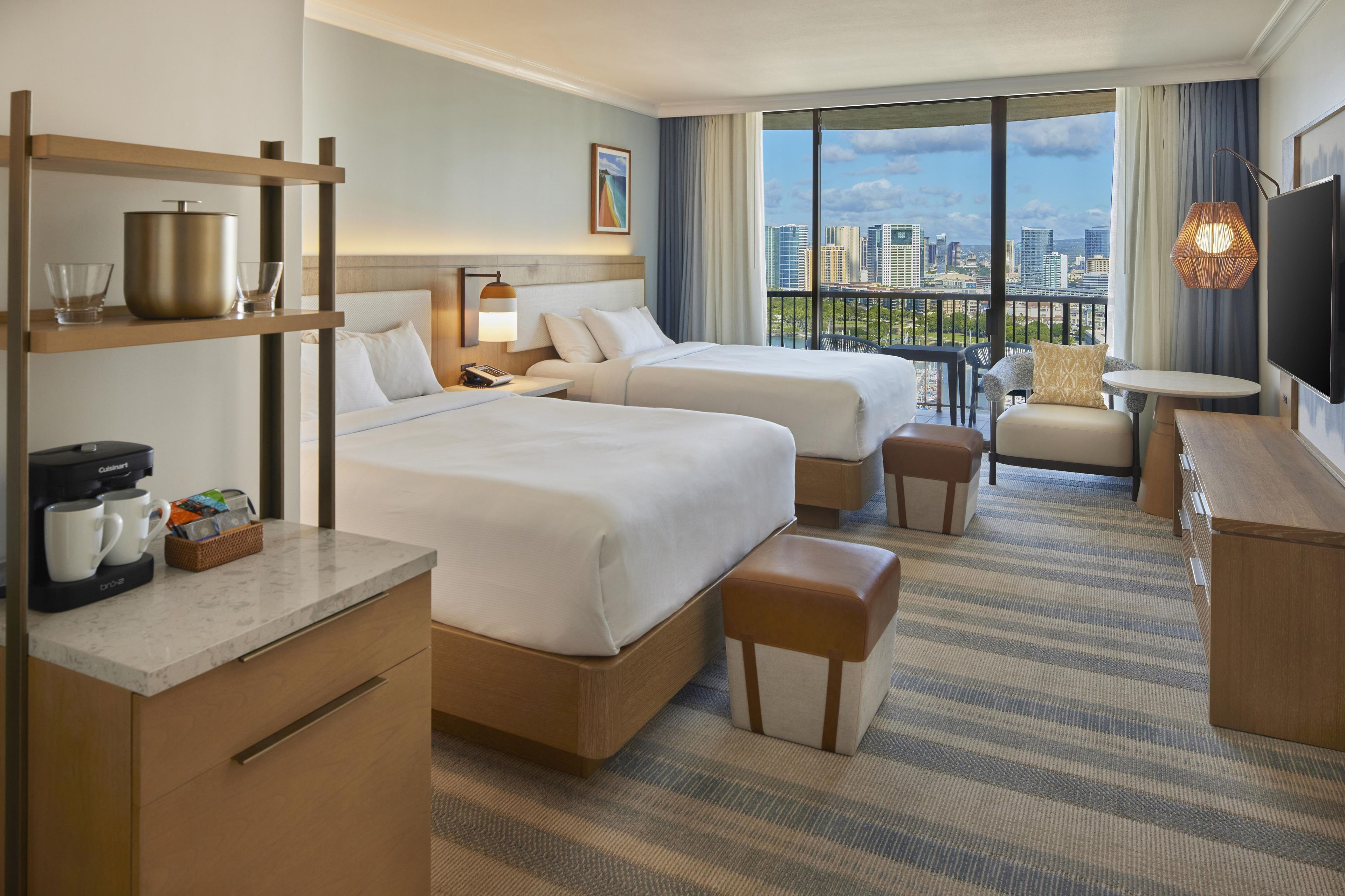 A hotel room with two beds, a desk, a coffee maker, and a TV.