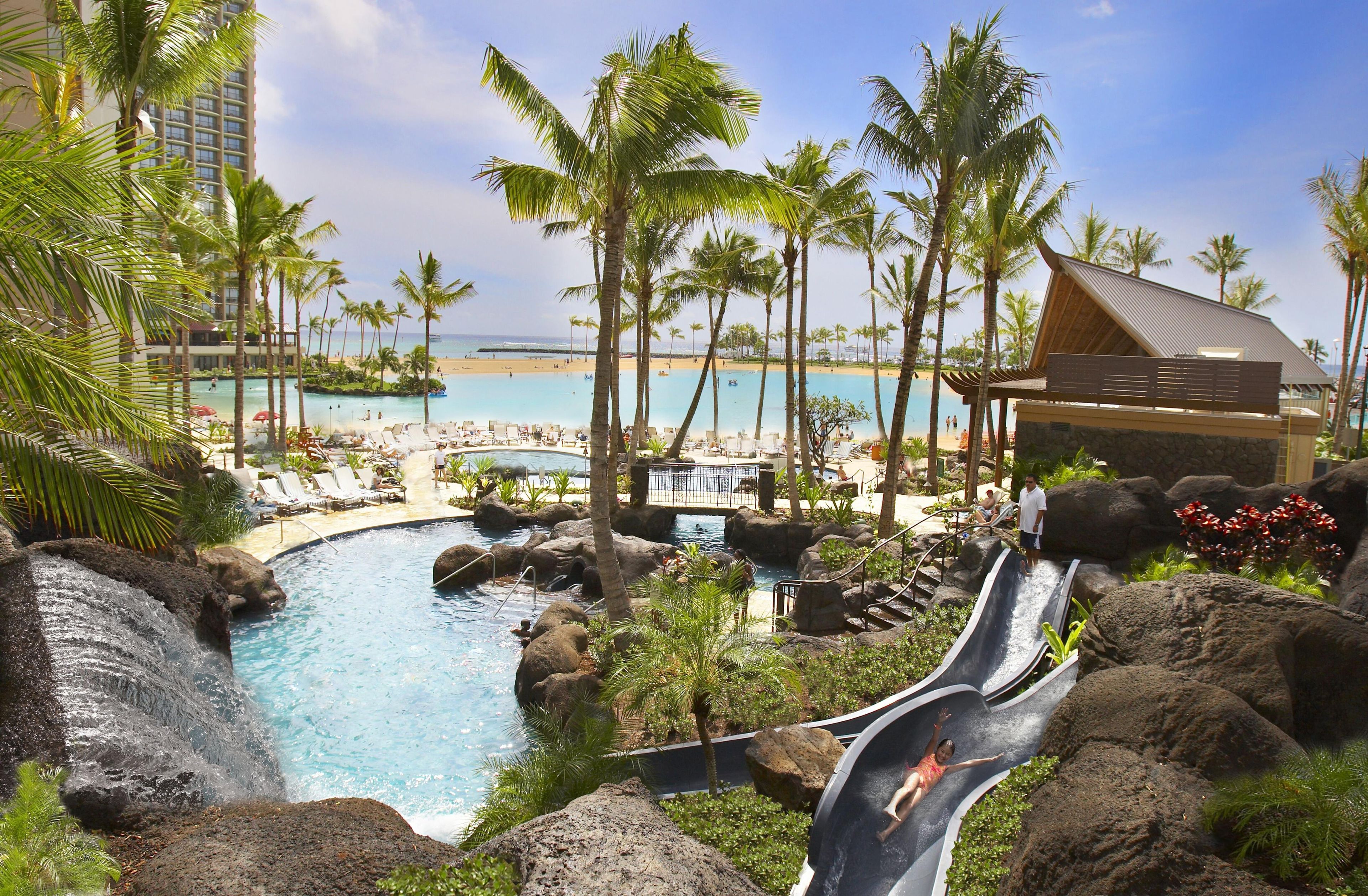 A resort with a pool, palm trees, and a beach view.