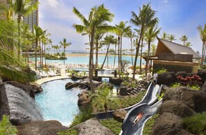 Et resort med pool, palmer og havudsigt.