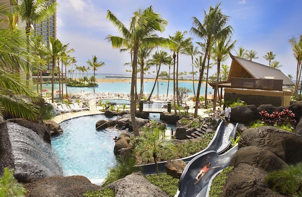 Un resort con piscina, palmeras y vista al mar.