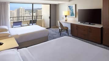 Une chambre d’hôtel avec deux lits, un bureau avec une télévision, une chaise et une vue sur le paysage urbain.