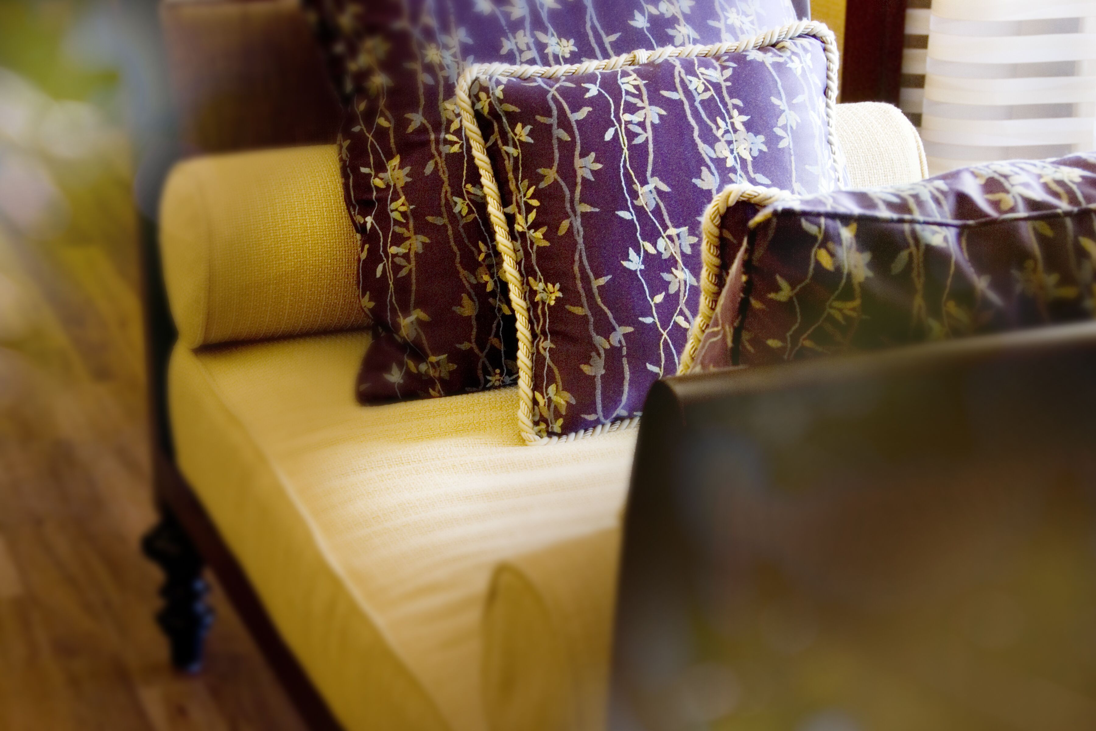 A sofa with floral-patterned cushions and a wooden frame.