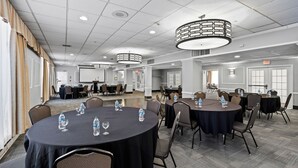 Un salón de conferencias con mesas redondas, sillas y botellas de agua.
