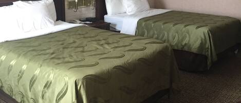 Ein Hotelzimmer mit zwei Betten, einer Wand mit Ziegeloptik, einem gerahmten Bild und einem Teppichboden.