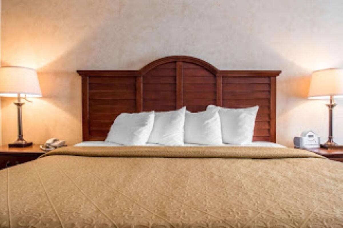 A neatly made bed with a wooden headboard, two bedside lamps, and a telephone on the nightstand.