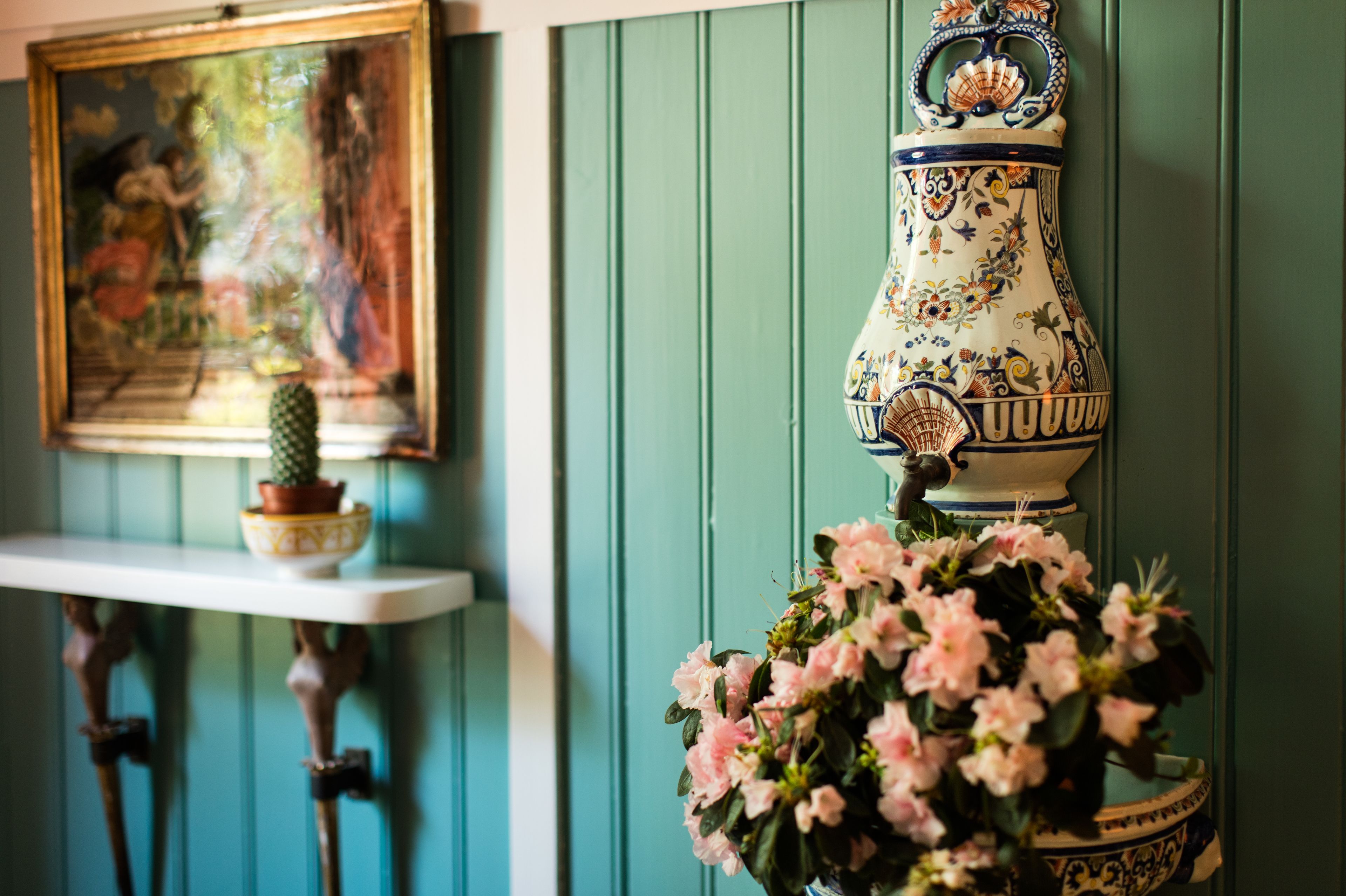 Eine dekorative Vase mit Blumen auf einem Regal, ein gerahmtes Bild und ein kleiner Kaktus auf einem Tisch.