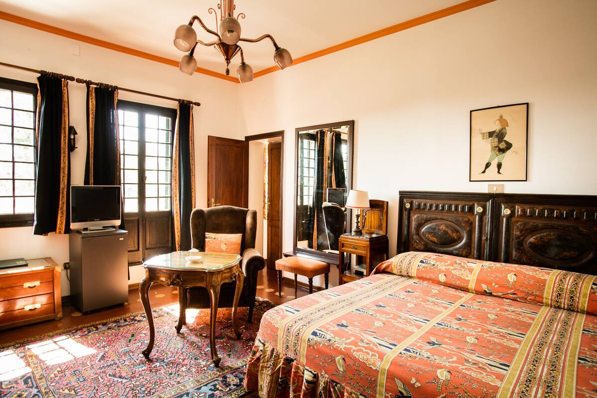 A room with a bed, a desk, a chair, a television, and a refrigerator.