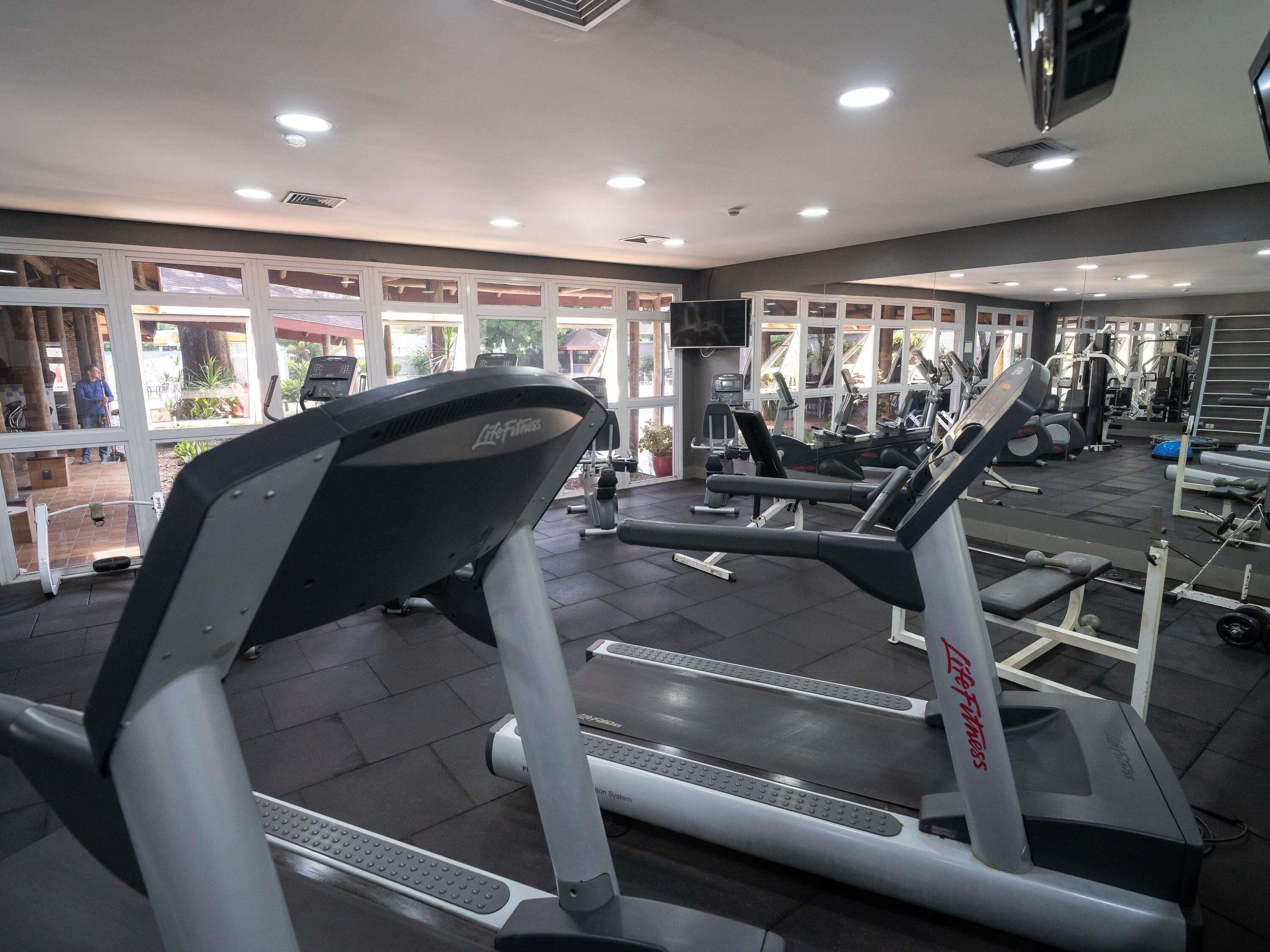 A gym with treadmills, weight machines, and a large window.