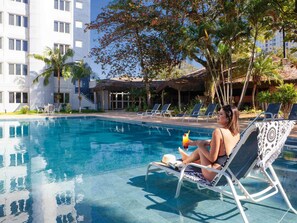 Una piscina con sillas de descanso y una persona relajándose.