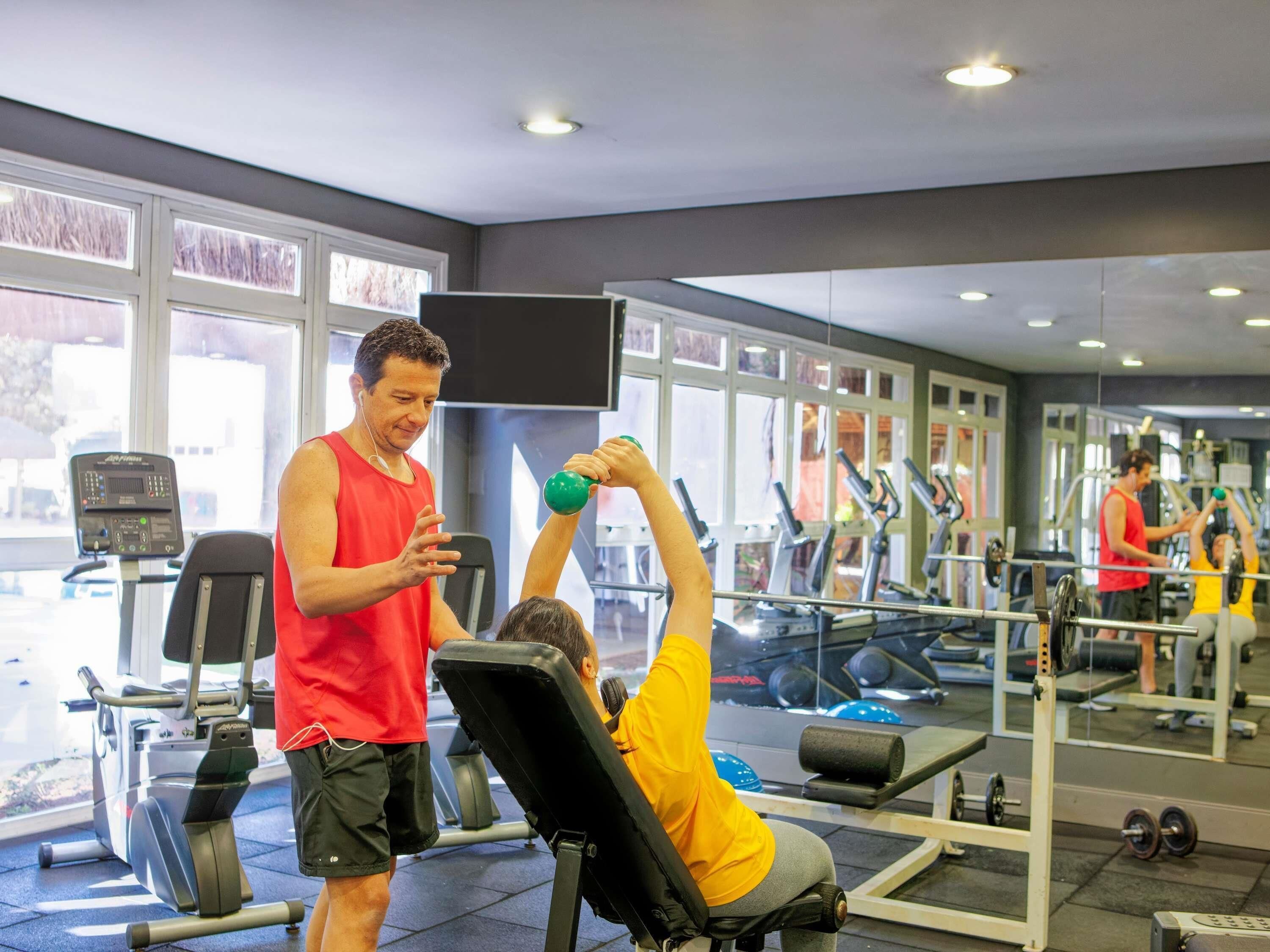 A gym with exercise equipment, a large window, and a mirror.