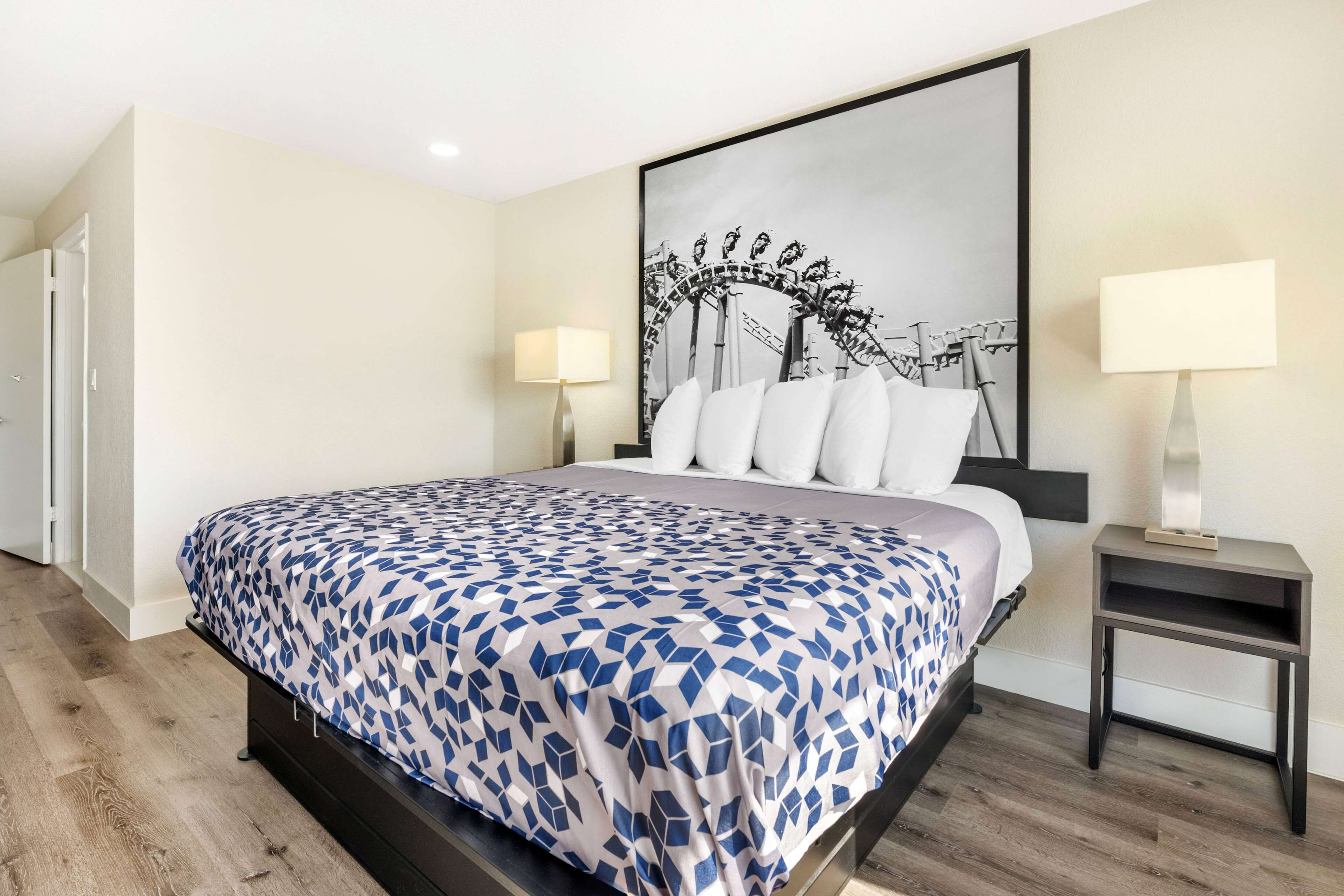 A modern hotel room with a large bed, a framed artwork above the bed, and two bedside lamps.