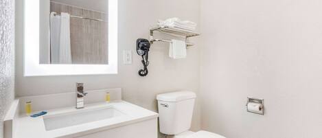 A bathroom with a white sink, a toilet, a towel rack, and a mirror.