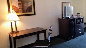 A hotel room with a desk, a chair, a lamp, a television, and a minibar. - Super 8 by Wyndham Wendover (Wendover)