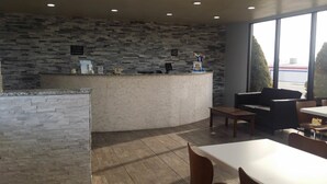 A reception area with a stone wall, a counter, a sofa, and a table. - Super 8 by Wyndham Wendover (Wendover)