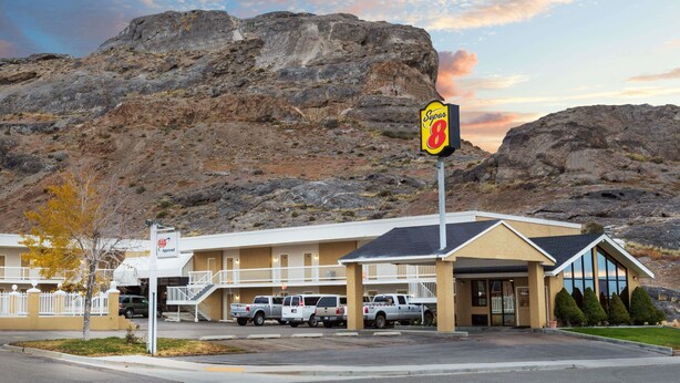 A Super 8 motel with a parking lot, a building with a balcony, and a mountainous backdrop. - Super 8 by Wyndham Wendover (Wendover)